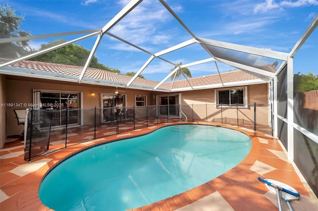 view of pool with glass enclosure, a patio area, and ceiling fan