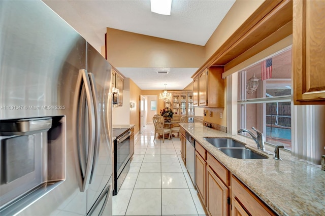 kitchen featuring pendant lighting, appliances with stainless steel finishes, sink, vaulted ceiling, and light tile patterned floors