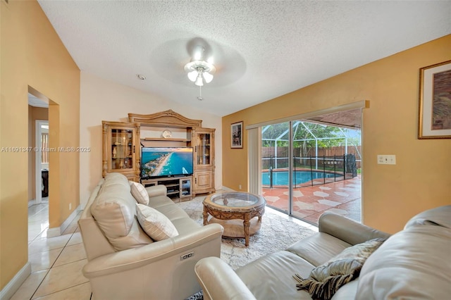 living room featuring light tile patterned flooring, a textured ceiling, and ceiling fan