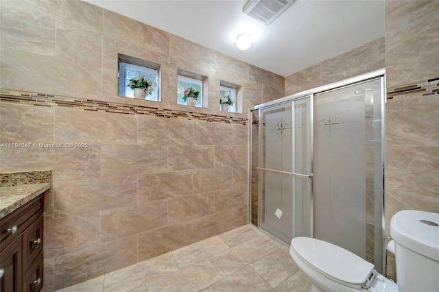 bathroom featuring toilet, tile walls, an enclosed shower, and vanity