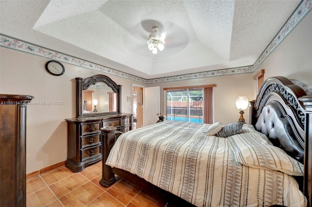 bedroom featuring a textured ceiling, tile patterned flooring, a raised ceiling, access to outside, and ceiling fan