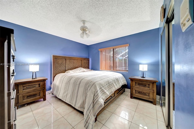 tiled bedroom with ceiling fan and a textured ceiling