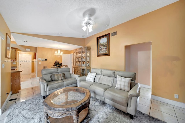 living room with vaulted ceiling, ceiling fan with notable chandelier, light tile patterned floors, and a textured ceiling