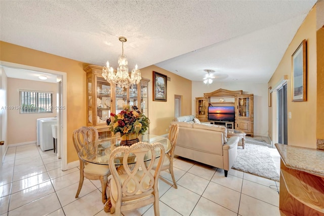 dining space with a chandelier, a textured ceiling, washer and dryer, and light tile patterned floors