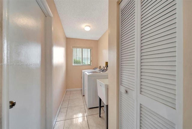 washroom featuring washer and dryer, a textured ceiling, and light tile patterned floors