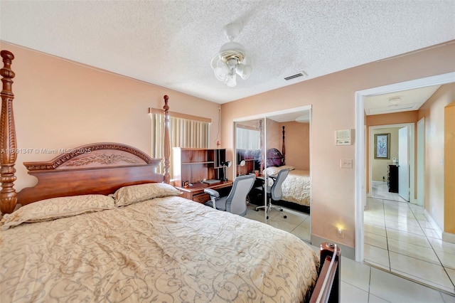 tiled bedroom with a textured ceiling and ceiling fan