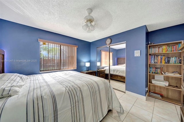 bedroom featuring a closet, ceiling fan, a textured ceiling, and light tile patterned flooring