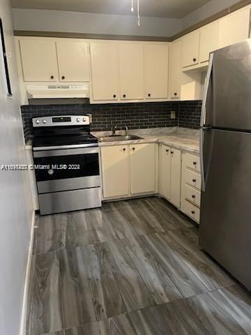 kitchen featuring white cabinetry, appliances with stainless steel finishes, dark hardwood / wood-style floors, and backsplash