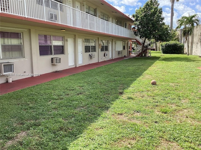 view of yard with a wall unit AC and a balcony