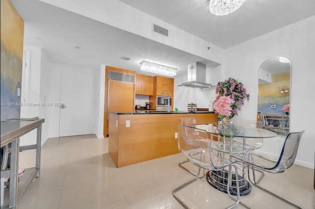 kitchen with wall chimney range hood, stainless steel microwave, and light tile patterned floors