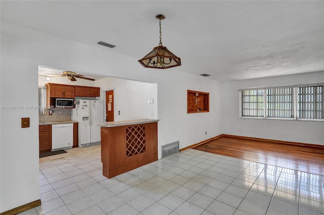 kitchen with kitchen peninsula, light tile patterned floors, white appliances, pendant lighting, and decorative backsplash