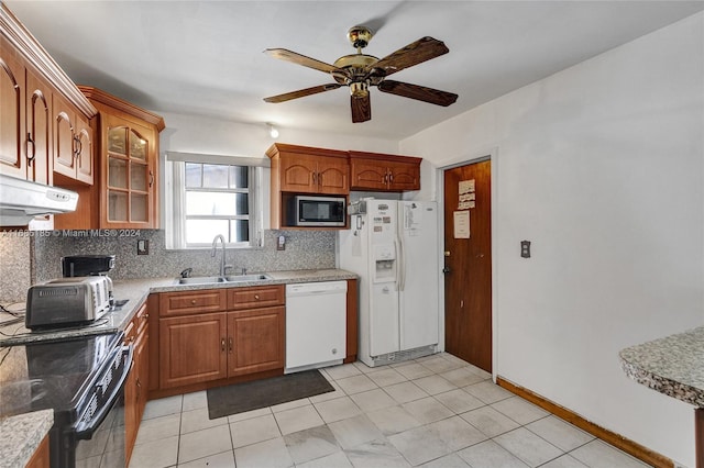 kitchen featuring sink, light stone countertops, ceiling fan, white appliances, and decorative backsplash