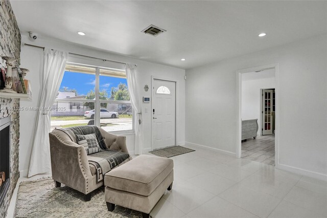 entryway with a stone fireplace and light tile patterned floors