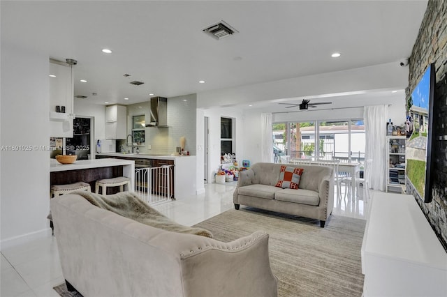 living room with sink, light tile patterned floors, and ceiling fan