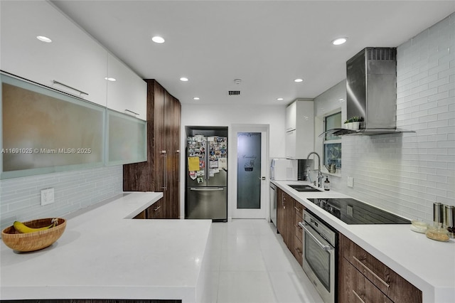 kitchen with sink, appliances with stainless steel finishes, white cabinetry, decorative backsplash, and wall chimney exhaust hood