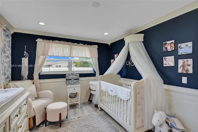 bedroom with crown molding, light hardwood / wood-style floors, and a crib