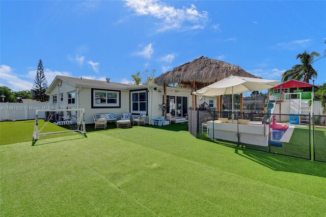 rear view of house featuring a swimming pool and a lawn