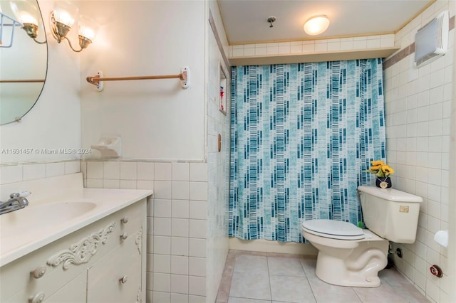 bathroom with toilet, vanity, tile walls, and tile patterned flooring