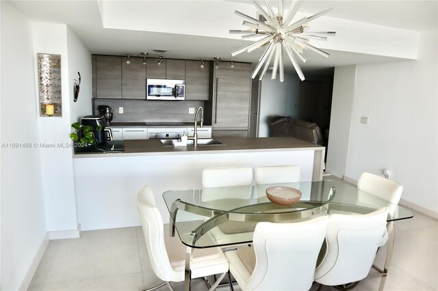 tiled dining area featuring a chandelier and sink