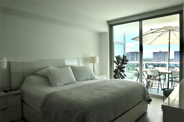 bedroom with floor to ceiling windows, concrete flooring, and access to outside