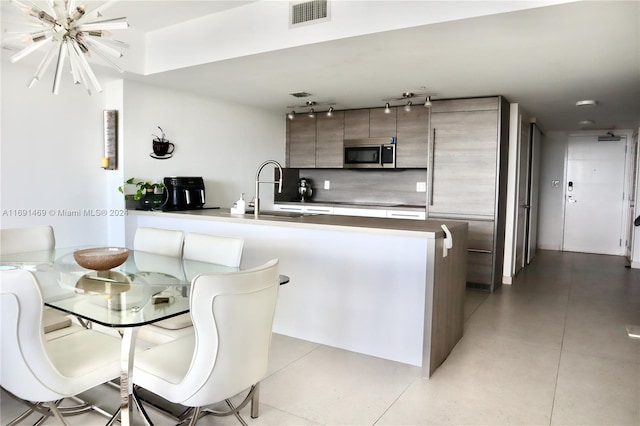 kitchen with kitchen peninsula, a notable chandelier, and sink