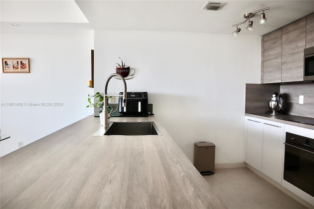 kitchen with decorative backsplash, white cabinetry, sink, and stainless steel appliances