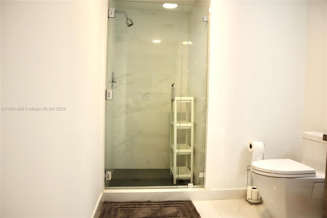 bathroom featuring toilet, tile patterned floors, and an enclosed shower