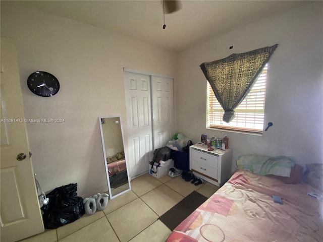 tiled bedroom with ceiling fan and a closet