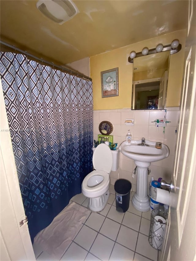 bathroom with tile patterned flooring, tile walls, and toilet