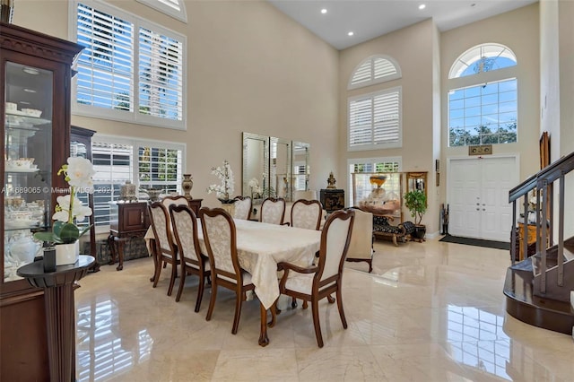 dining area featuring a towering ceiling and a healthy amount of sunlight