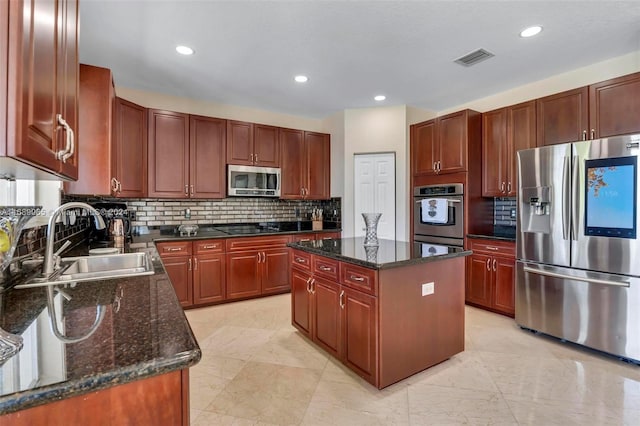 kitchen featuring dark stone countertops, a center island, sink, and stainless steel appliances