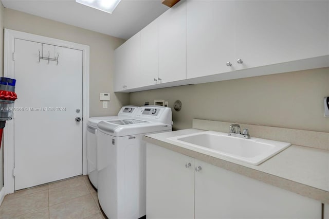 washroom with cabinets, light tile patterned flooring, washer and clothes dryer, and sink