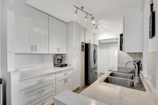 kitchen featuring white cabinetry, sink, and stainless steel refrigerator