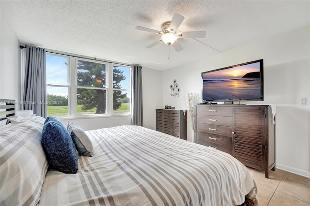 bedroom with a textured ceiling, light tile patterned floors, and ceiling fan