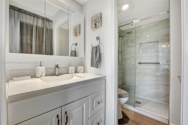 bathroom with hardwood / wood-style floors, an enclosed shower, vanity, and toilet