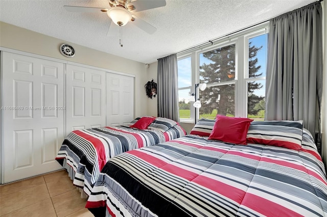 bedroom with a closet, a textured ceiling, ceiling fan, and light tile patterned floors