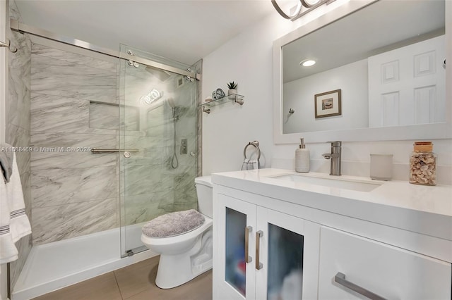 bathroom featuring tile patterned flooring, vanity, toilet, and a shower with shower door