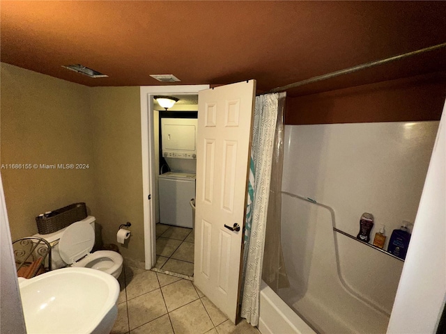 bathroom featuring stacked washer / drying machine, shower / bath combo with shower curtain, toilet, and tile patterned flooring