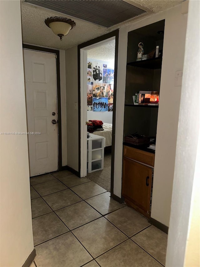 hallway featuring tile patterned flooring and a textured ceiling