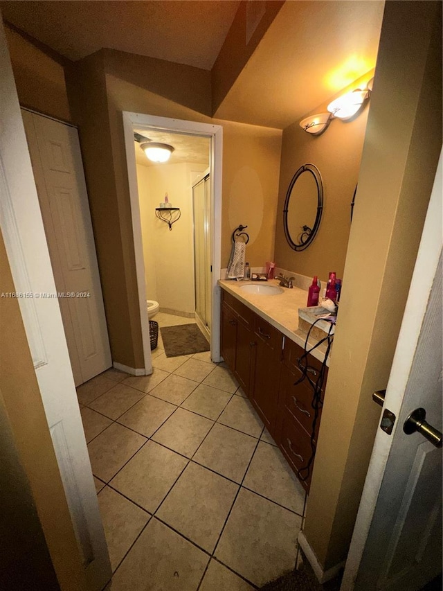 bathroom with tile patterned flooring, vanity, toilet, and a shower