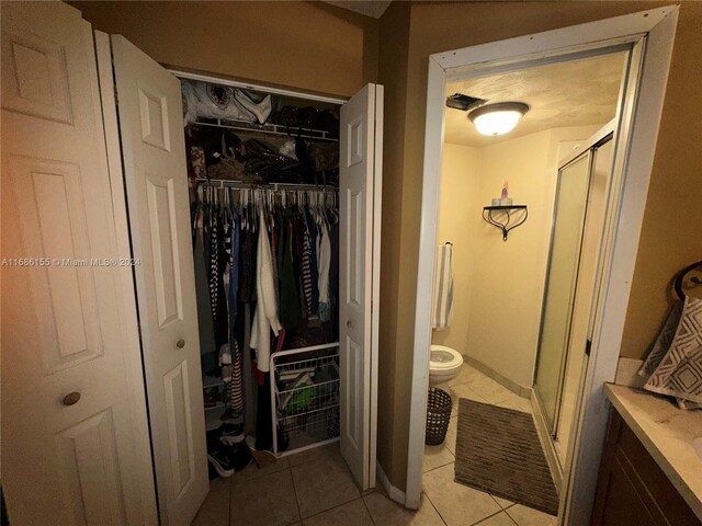 interior space with walk in shower, toilet, and tile patterned floors