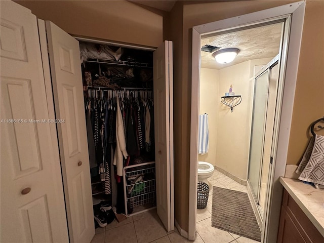 bathroom with walk in shower, toilet, vanity, and tile patterned floors