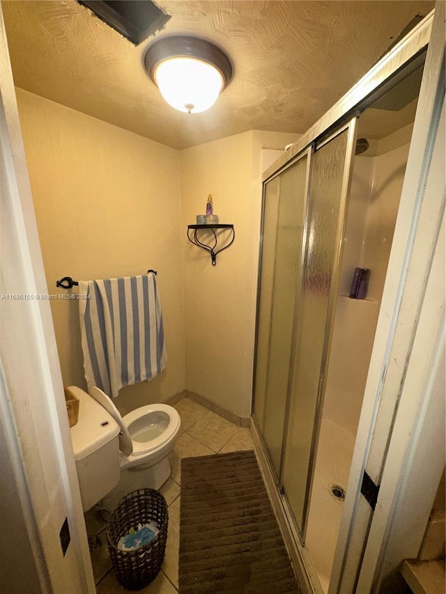 bathroom with walk in shower, toilet, and tile patterned floors