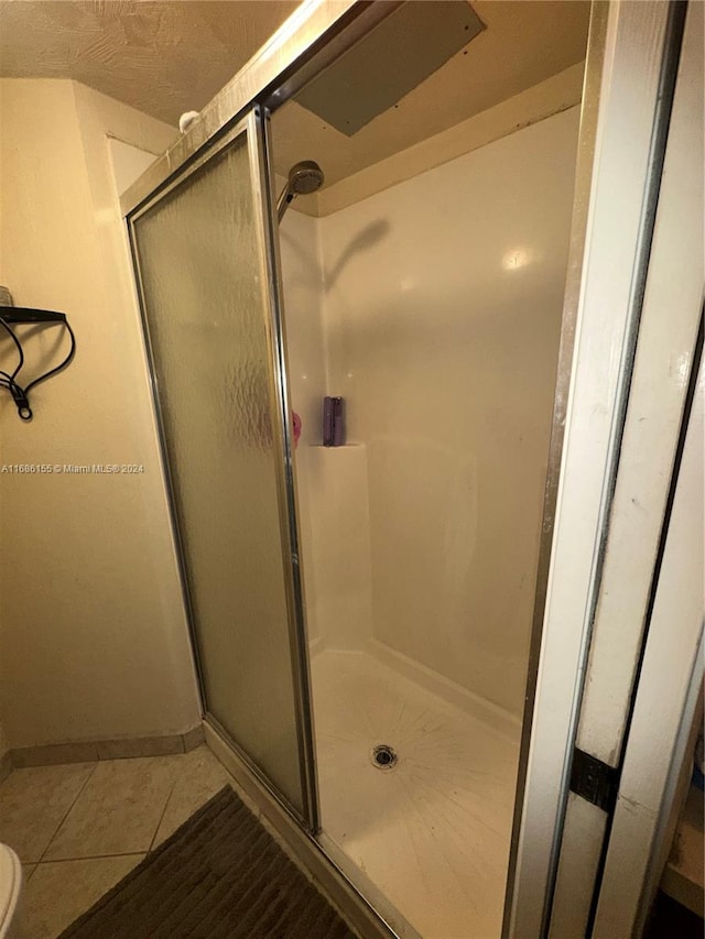 bathroom featuring tile patterned floors and a shower with shower door