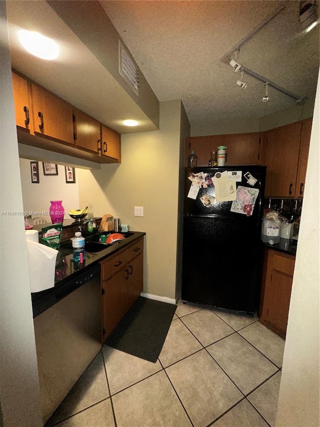 kitchen with black fridge, rail lighting, light tile patterned floors, a textured ceiling, and stainless steel dishwasher