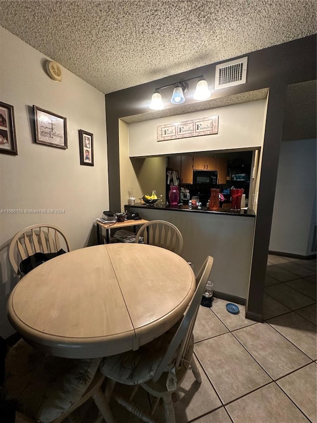 tiled dining space featuring a textured ceiling