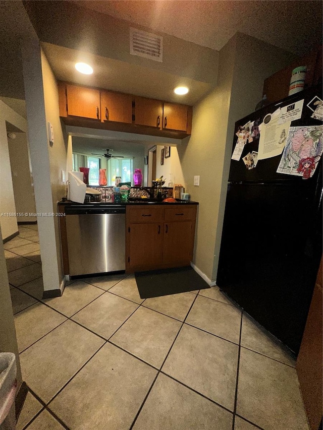 kitchen with stainless steel dishwasher, light tile patterned floors, and black fridge