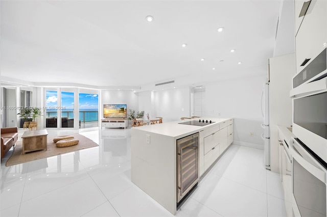 kitchen featuring wine cooler, floor to ceiling windows, white cabinets, a center island, and oven