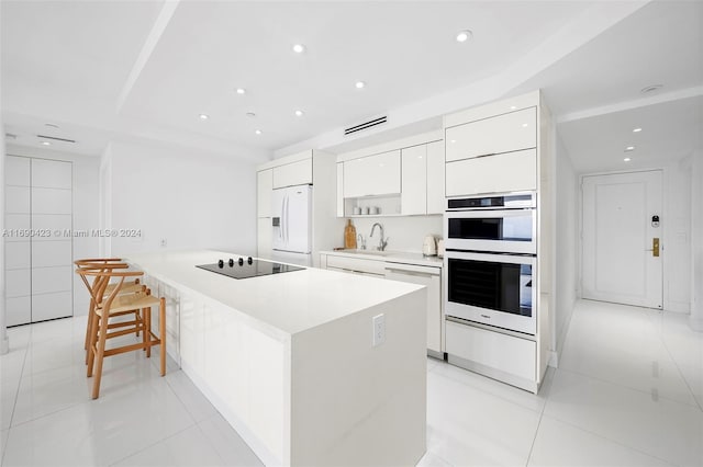 kitchen featuring white cabinetry, a center island, light tile patterned floors, and white appliances