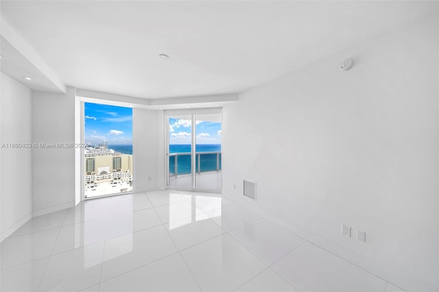 tiled spare room with a water view and a wall of windows